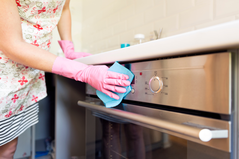 Woman in pink gloves cleaning stove