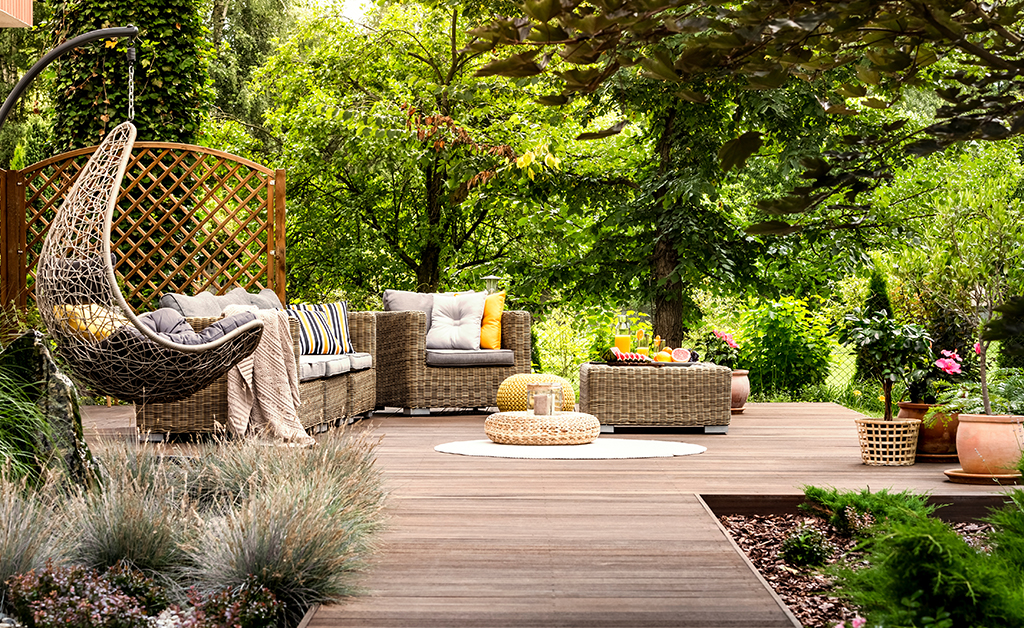 Beautiful wooden terrace with garden furniture surrounded by greenery