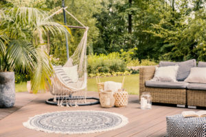 Pillows on hammock on terrace with round rug and rattan sofa in the garden