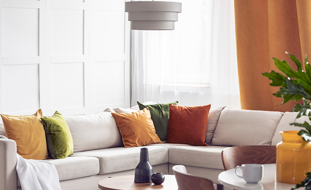 Living room with light couch and orange pillows and an orange curtain